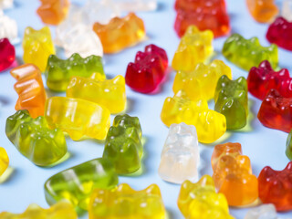 Delicious bright gummy bears on a blue background, flat lay