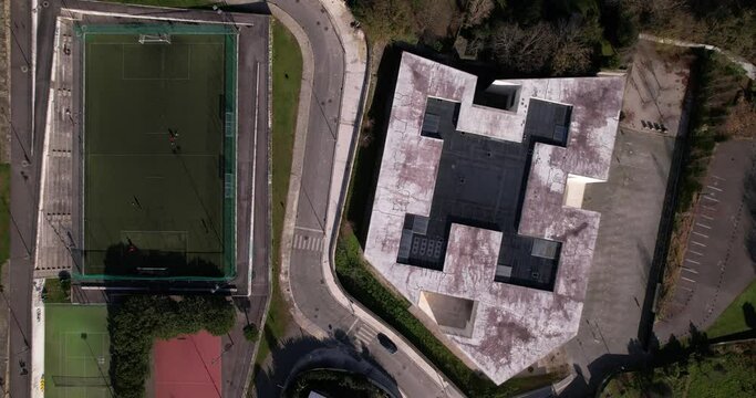 Santo Tirso, Portugal, January 1, 2022: DRONE AERIAL FOOTAGE - Flyover view of multi-functional sports area with tennis courts, basketball court, and football pitch and Altice Call Center building.