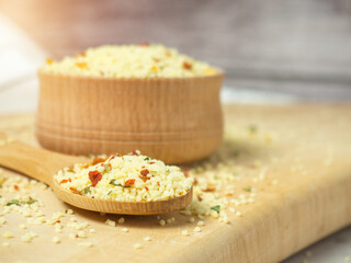 couscous mix with spices and tomatoes in a wooden bowl and spoon close-up