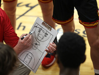A basketball play is drawn up on a dry erase board during a timeout. - Powered by Adobe