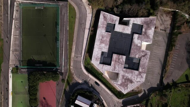 Santo Tirso, Portugal, January 1, 2022: DRONE AERIAL FOOTAGE - Flyover view of multi-functional sports area with tennis courts, basketball court, and football pitch and Altice Call Center building.