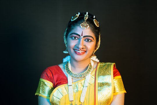 Portrait shot happy smiling Indian Bharatnatyam dancer on stage looking at camera - concept of classical dance, confident and traditional artist.
