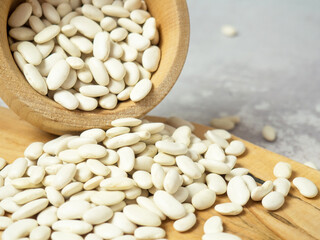 white beans in a wooden cup and spoon are scattered on the table