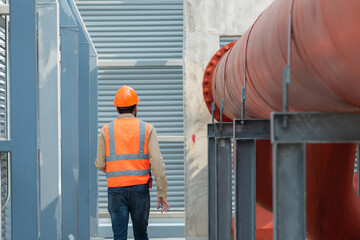 worker in uniform with helmet. worker checking drawing on cooling tower plant. Engineer under...