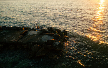 Aerial view of an amazing sunset at the seaside. Seashore landscape with turquoise water color and beautiful golden hour light.