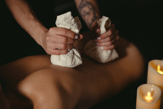 beautiful girl is given a back massage with bags of useful herbs