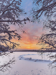 Winter sunset near the Finnish Tuusula lake: shore, snow on ice as oval, nature of northern Europe, framed.