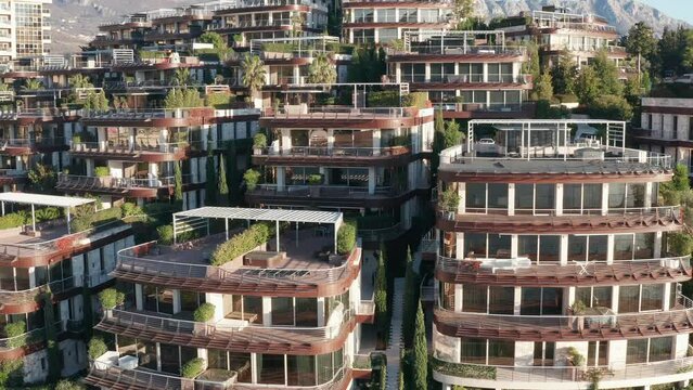Luxury apartment buildings on the hillside - homes with view. Residences in a vacation tourist destination on the Mediterranean sea coast. Rooftops of green eco houses - aerial drone view on sunny day