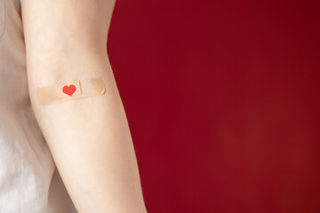 blood donation,patient hand with a plaster heart on a red background