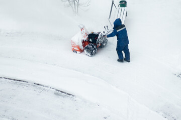 janitor cleans the street from snow