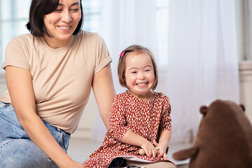 happy family portrait of mother with daughter with down syndrome at home with toys