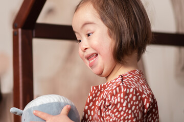 cute baby girl with down syndrome plays with toys