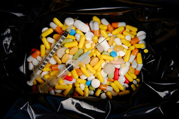 Expired tablets with disposable used syringes are in a garbage bag.The concept of spent medicines...