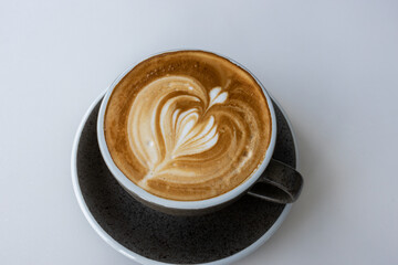 Hot latte With art milk froth in a coffee cup on a white table.