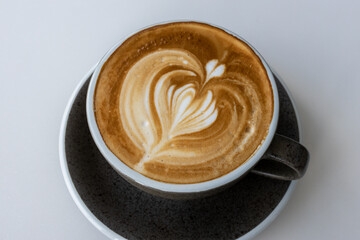 Hot latte With art milk froth in a coffee cup on a white table.