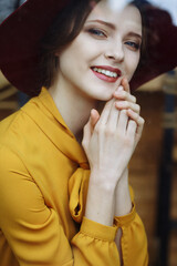 portrait of a girl in a cafe with a cup of coffee and a hat.portrait of sensual young girl wearing floppy hat and blouse with bow. Beautiful brunette woman in cafe holding cup of coffee