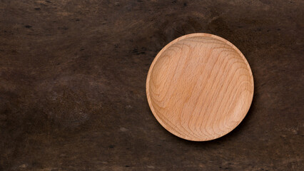 empty wooden plate on a dark wood surface, food or product photography background or backdrop, top view with copy space