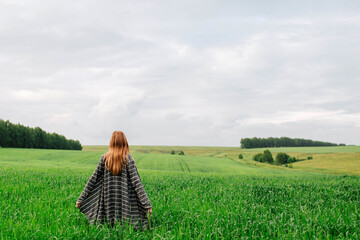 Girl in the field. Green field. A person admires nature. Landscape. Country life
