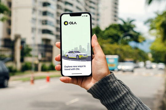 Girl on the street holding smartphone with Ola Cabs app on the screen waiting for car to arrive. Rio de Janeiro, RJ, Brazil. February 2022