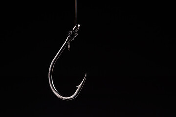 Fishing hook on a black background. trap, catch on, risk. Business concept idea