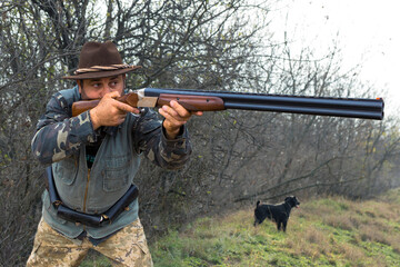 Hunter man in camouflage with a gun during the hunt in search of wild birds or game. Autumn hunting...