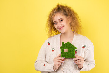 Happy house buyer. A young girl holds a model of a green house in her hands. The concept of green energy, ecology.