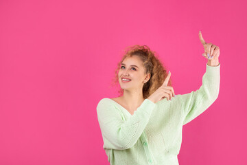 Fototapeta premium A young girl with curly hair points with a gesture on a studio background.