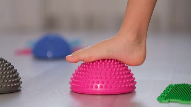 Little boy walking over spiked half balance massage balls. Flat feet correction exercise. close up Shot video. Slow motion