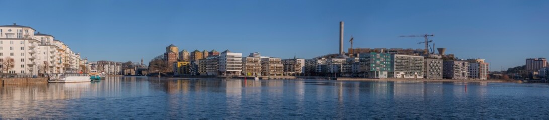 Fototapeta premium Panorama view, boats and modern apartment houses at the piers in the districts around the bay Hammarby sjö in the district Södermalm a sunny winter day in Stockholm