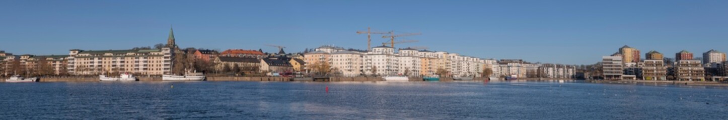 Fototapeta premium Panorama view, boats and modern apartment houses at the piers in the districts around the bay Hammarby sjö in the district Södermalm a sunny winter day in Stockholm
