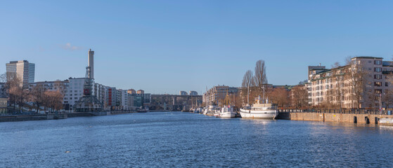 Obraz premium Panorama view, boats and modern apartment houses at the piers in the districts around the bay Hammarby sjö in the district Södermalm a sunny winter day in Stockholm