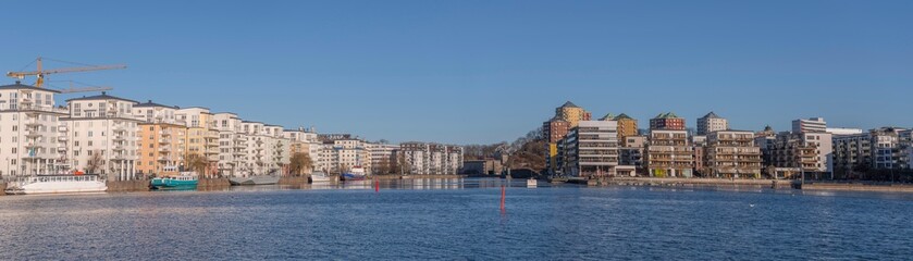 Fototapeta na wymiar Panorama view, boats and modern apartment houses at the piers in the districts around the bay Hammarby sjö in the district Södermalm a sunny winter day in Stockholm
