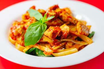 Tagliatelle pasta with chicken breast pieces in a seasoned tomato sauce