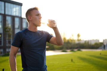 Close up shot of a male who finished her run,  drinking the water from his reusable plastic bottle...