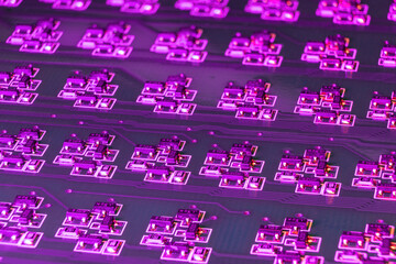 Close-up of an electronic circuit board with many SMD components illuminated by ultraviolet light. Complex logical electronic system built on smd components