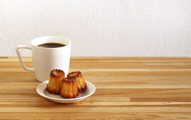 Canelle is a traditional french pastry with cup of tea wooden table , copy space