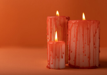 Composition from a group of scary bloody candles burning on an orange background.Copy space on an orange paper background. Black magic ritual or scary Halloween rite.DIY Halloween decor.