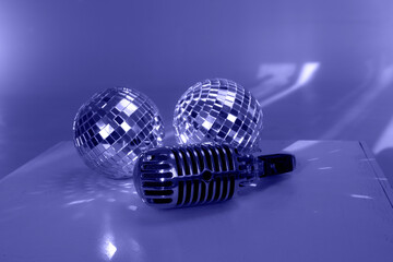 Vintage microphone and two mirror disco balls on wooden cube; blue or Very Peri color palette