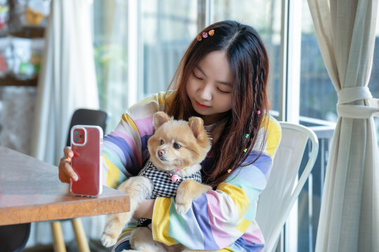 Friendship and happiness Concept. Young beautiful woman taking selfie with her dog at home. Pomeranian Spitz selfie with owner