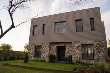 Architecture. Steel framing construction. Modern house in the suburbs at sunset. The green grass, front yard and house facade with a beautiful dusk light.