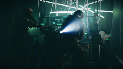 Tactical team in armor breaking into dark room and putting handcuffs on hacker while arresting...