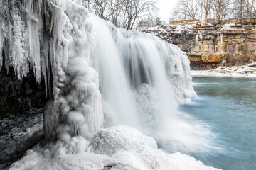 Upper Cataract Falls, a waterfall on Mill Creek in Owen County, Indiana, flows partially frozen in winter adorned with icicles and sculptures of snow. - 486761886