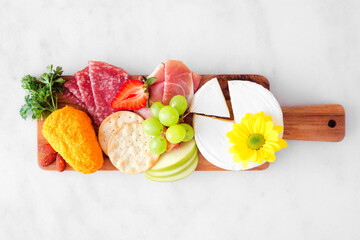 Spring or Easter theme charcuterie board against a white marble background. Selection of cheese,...