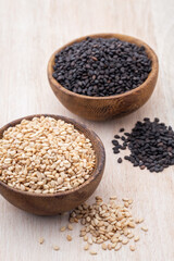White sesame and black sesame seed on wooden bowl.