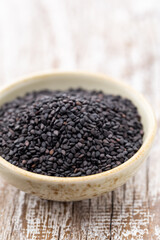 Bio natural black sesame seeds on white bowl.