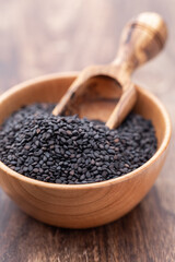 Bio natural black sesame seeds on wooden bowl.