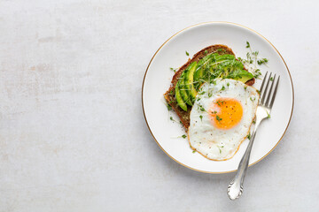 Keto breakfast fried egg, avocado and bread in a white plate. Keto diet concept.