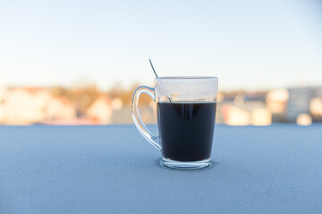 coffee mug. glass cup of coffee on the balcony railing with urban view. A cup of espresso during a...