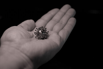 The man has a virus in his hand. A powerful angry virus with a face. The coronavirus is slightly blurred.