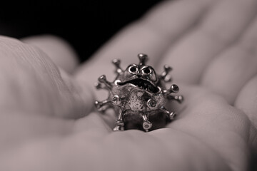 The man has a virus in his hand. A powerful angry virus with a face. The coronavirus is slightly...